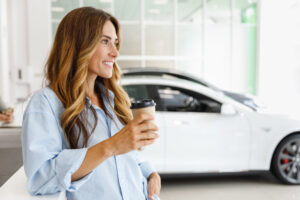 Woman in a dealership with a coffee smiling